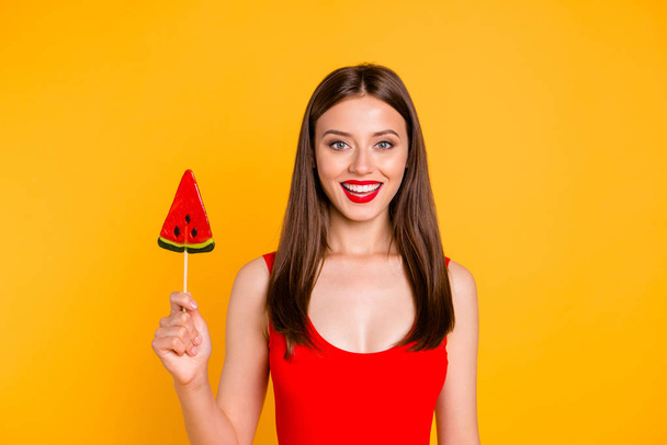 Yummy! Sweet summer! Close up portrait of attractive lovely woman holding piece on caramel fruit on stick, isolated on bright yellow background - Photo, Image