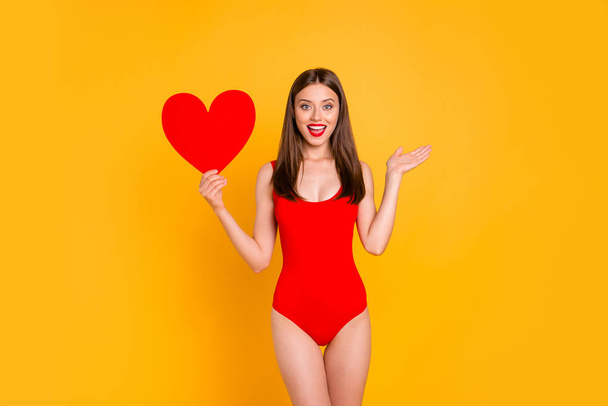 Lovely summer! Portrait of cute brunette woman with big paper carton red heart in hand isolated on yellow vivid background - Фото, зображення