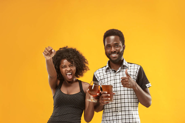 La pareja afro o jóvenes felices riendo y bebiendo cerveza en el estudio
 - Foto, imagen