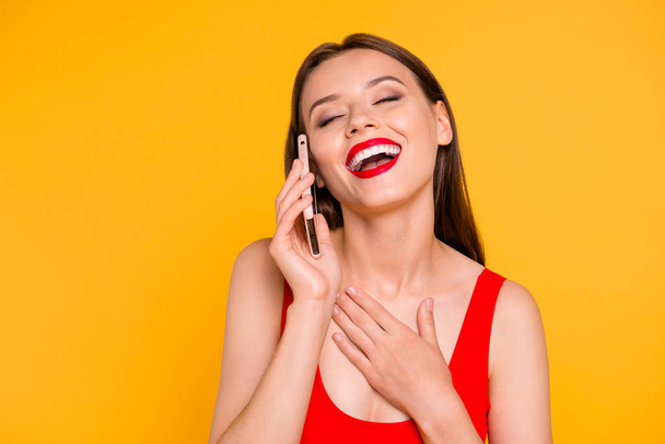 Close up portrait of trendy young woman laughing while talking on the cellular  isolated on yellow background - Valokuva, kuva