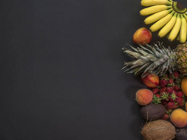 тропические ананасы мини-бананы апельсины кокосовый орех и другие вкусные фрукты темный фон копировать пространство
 - Фото, изображение