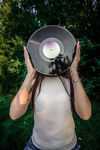 Girl holding a vinyl record in her hands, covering her face - Fotografie, Obrázek