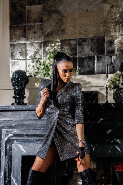 Stylish studio portrait of brunette woman in fashionable clothes standing in luxury interior - Фото, зображення