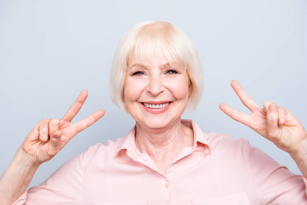Old lady showing v-sign victory peace gesture, smiling on grey background - Foto, Imagem