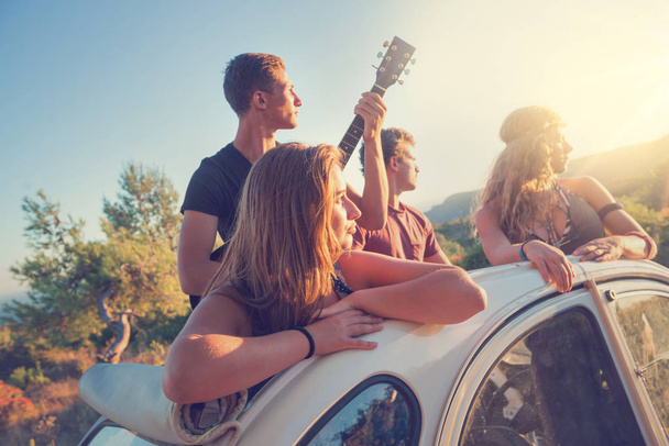 Skupina šťastných lidí v autě při západu slunce v létě. - Fotografie, Obrázek
