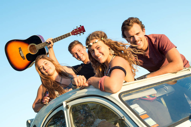 Ομάδα των ευτυχισμένων ανθρώπων σε ένα αυτοκίνητο στην Δύση του ηλίου το καλοκαίρι. - Φωτογραφία, εικόνα