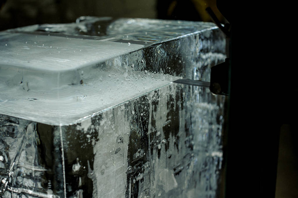 Special tool cutting a big clear ice cube on the ice production plant in the dark - Fotó, kép