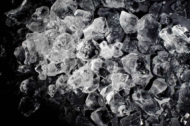 Textured background of a small clear ice cubes in the heap on the on the black background - Foto, Imagen