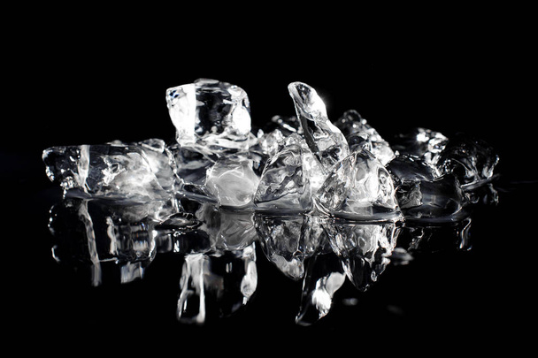 Heap of a small white and transparent ice cubes isolated on the black background reflecting - Foto, immagini