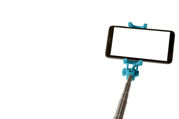 Monópodo para selfie con teléfono inteligente. Selfie stick con smartphone aislado sobre fondo blanco
 - Foto, Imagen