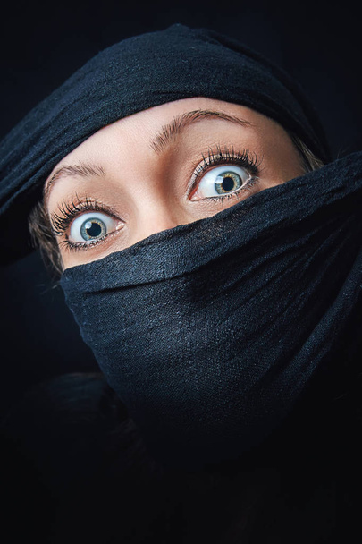 Nainen kasvot lähikuva vain silmät näkyvissä, loput kasvot on peitetty musta huivi
 - Valokuva, kuva