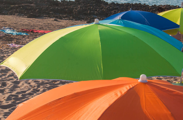 Цветные и цельные пляжные зонтики в жаркий летний день
 - Фото, изображение
