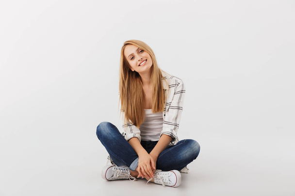 Arckép vidám fiatal lány alkalmi lábakkal ült elszigetelt átment fehér háttér - Fotó, kép