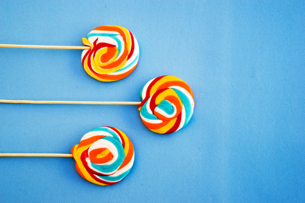 Kleurrijke lollipop op een blauwe achtergrond. Rode, witte en blauwe strepen op een snoepje. Minimale concept. Candy shop Modelle. - Foto, afbeelding
