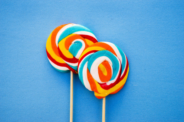Colorful lollipop on a blue background. Red, white and blue stripes on a candy. Minimal concept. Candy shop series. - Photo, Image