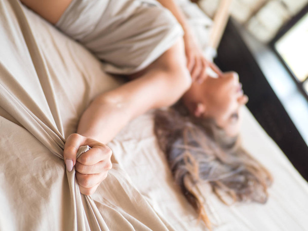 Slanke, perfecte en prachtige woamn op bed. Bijgesneden afbeelding van erotisch liggend op bed mooie vrouw in de slaapkamer. Verfrommeld wit beddengoed. - Foto, afbeelding