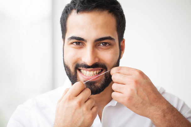 Zubní zdraví. Muž s krásným úsměvem Flossing zdravé zuby. Obraz s vysokým rozlišením. - Fotografie, Obrázek