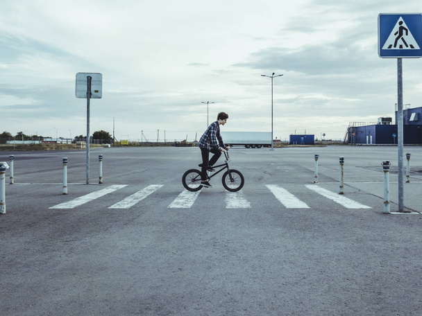 young man riding a bmx bicycle bike crossing the urban street  - Фото, изображение