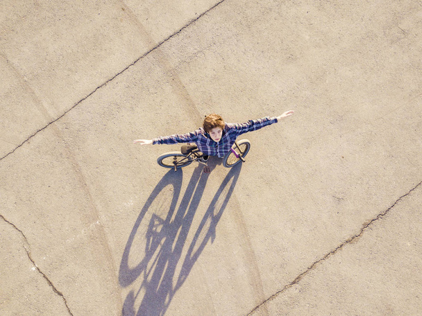 Widok z lotu ptaka młodego człowieka z uniesionymi rękoma z rowerów stojących na sphalt kopia przestrzeń wolności koncepcji - Zdjęcie, obraz