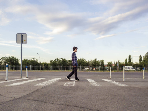 wide angle teenager boy walking on zebra across the road street - Φωτογραφία, εικόνα