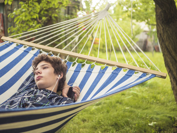 joven adolescente macho durmiendo en la hamaca en el jardín en un día de verano
 - Foto, Imagen