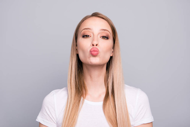 Close up portrait of of lovely, sweet and dreamy blondy girlfriend sending air kiss with plump lips isolated on gray background - Foto, imagen