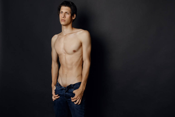 Male model in denim blue jeans on black background in studio isolated - Foto, Imagen