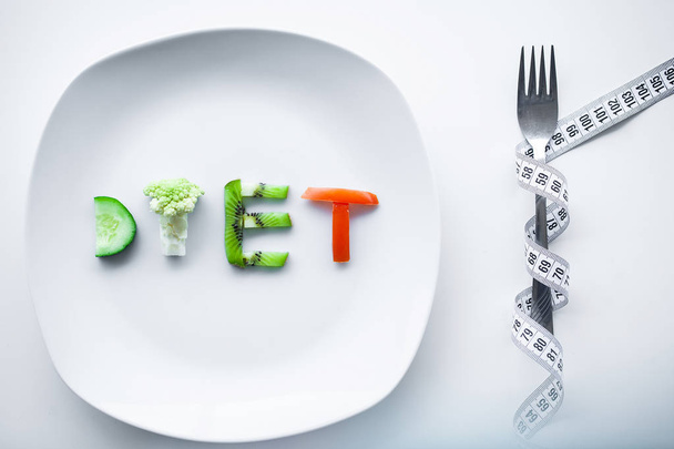 Diet or weight control concept. Centimeter tape and fork on a white background with a place for inserting text. concept of health, weight loss, diet, proper nutrition. - Photo, Image