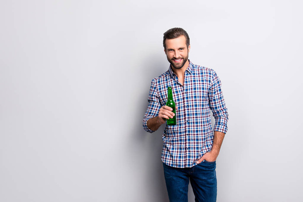 Portrait of cheerful excited relaxed carefree guy drinking beer from bottle holding in hand wearing checkered blue shirt denim jeans isolated on gray background copy-space - Fotografie, Obrázek