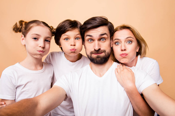 Self portrait of young attractive adorable grimacing family, bearded father, blonde mother and their little children, boy and girl, wearing white T-shirts, holding air in cheeks - Foto, afbeelding