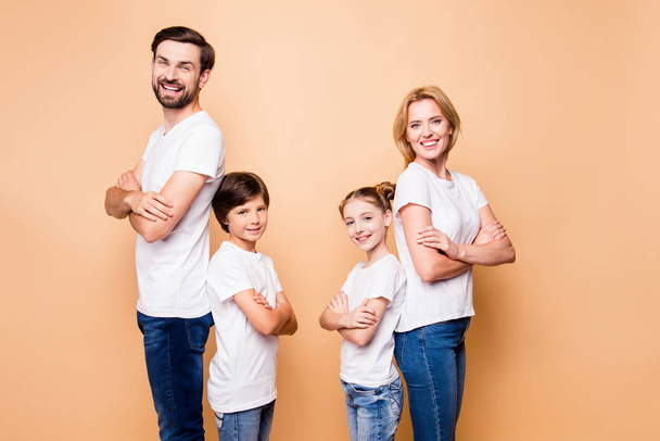 Portrait of adorable attractive happy smiling confident family, bearded father, blonde mother spouses standing back to back with their little children wearing jeans and white T-shirts, folded hands - Photo, image