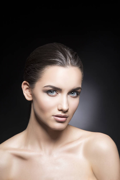 Retrato de mujer joven con maquillaje natural sobre fondo negro
 - Foto, Imagen
