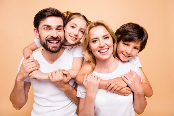 Closeup portrait of young lovely smiling family, bearded father, blonde mother, boy and girl offspring wearing white T-shirts, children hugging parents spouses - Photo, Image