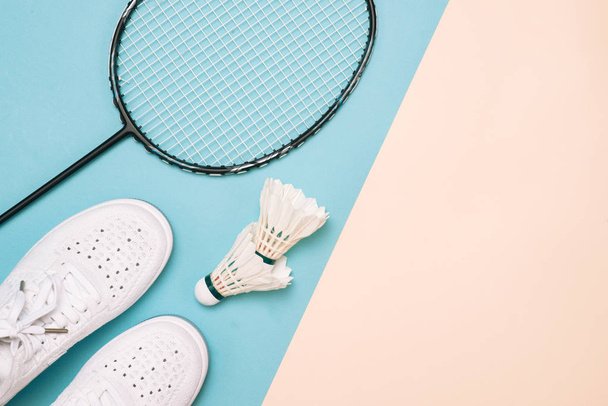 Shuttlecock and badminton racket with sport shoes on pastel color background - Фото, изображение