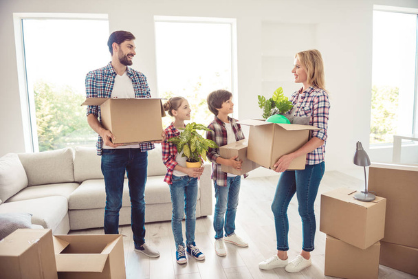 Young happy smiling family four persons holding carton boxes packages with stuff things in light living room, moving to new flat, improvement - Foto, Bild