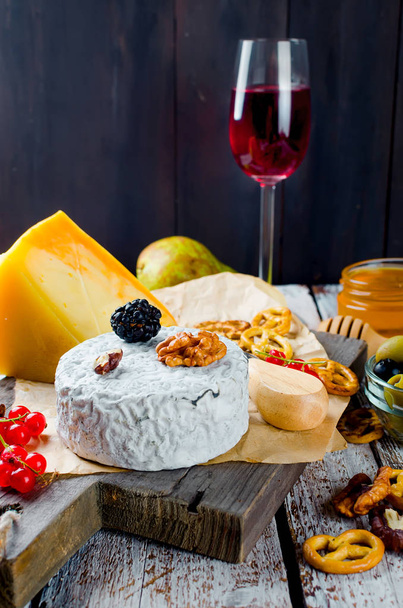 cheese sliced, cheese with mildew, hard cheese, olives, walnuts, peanuts, honey, a glass of wine, a romantic dinner, a meal for the shurman - Foto, Bild