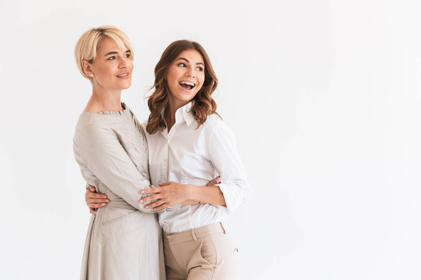 Photo of young happy woman hugging with her mother isolated over white background. Looking aside. - Foto, imagen