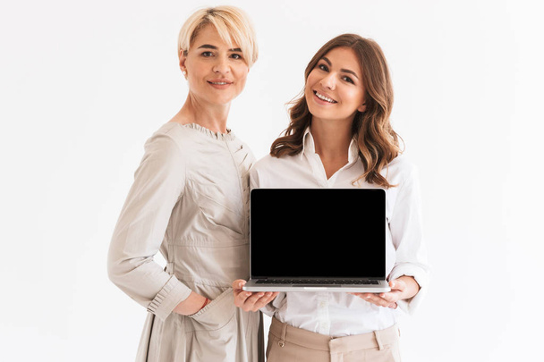 Photo of young happy woman with her mother using laptop computer showing display isolated over white background. - Photo, image