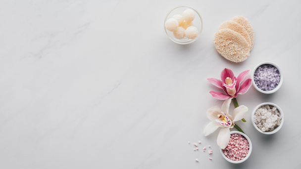 pohled shora krásné květy orchidejí, mořská sůl do misky a houby na bílém pozadí  - Fotografie, Obrázek