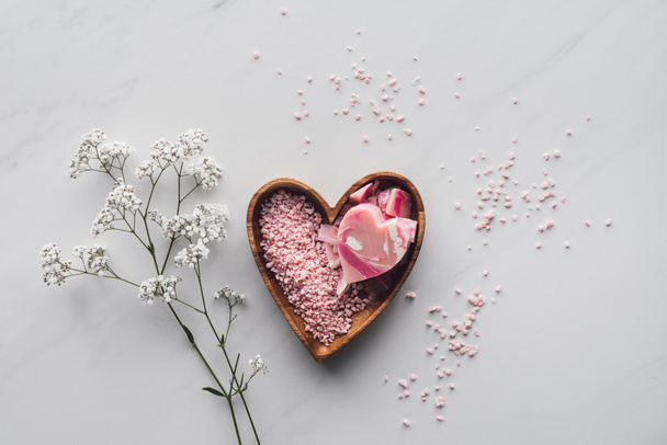 top view of pink sea salt and handmade soap in heart shaped bowl on white - Фото, зображення