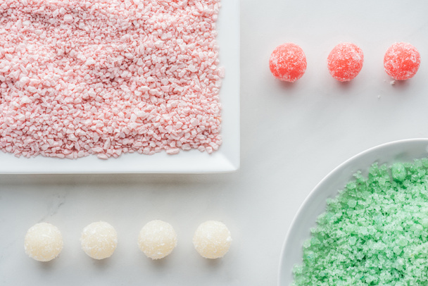 bovenaanzicht van groen en roze zee zout en handgemaakte zeep op wit - Foto, afbeelding