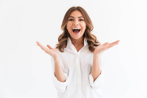 Portrait of excited young woman with long brown hair screaming and throwing up hands isolated over white background in studio - Photo, image