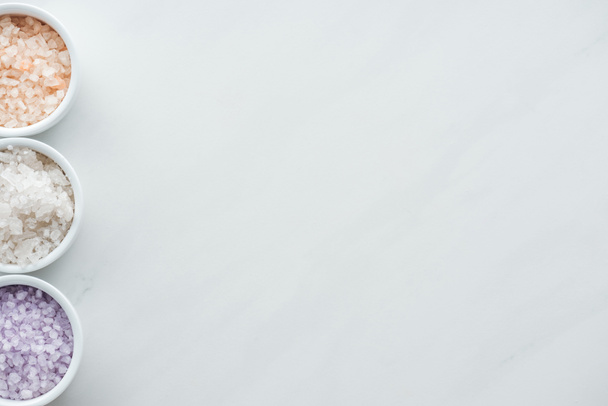 το Top view πολύχρωμο θαλασσινό αλάτι σε μπολ σε λευκό φόντο  - Φωτογραφία, εικόνα