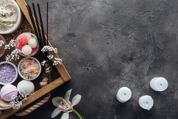 Draufsicht auf Wellness- und Badezubehör in Holzkiste, Orchidee und Kerzen auf grauem Hintergrund  - Foto, Bild