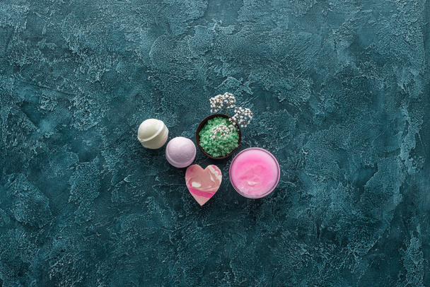 top view of green sea salt, beautiful small flowers and handmade soaps on grunge background - Photo, Image