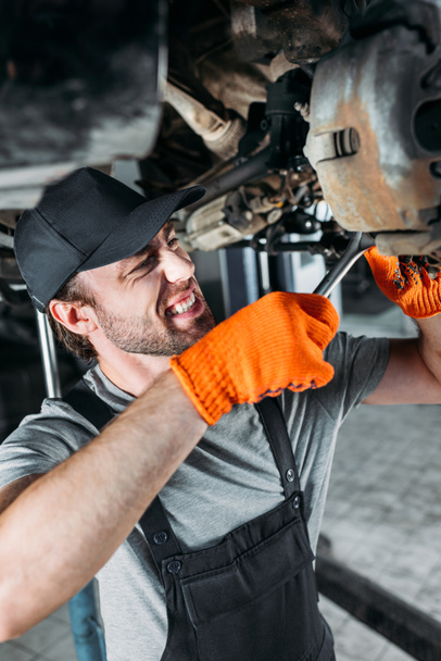 professional mechanic repairing car without wheel in workshop - Foto, Bild