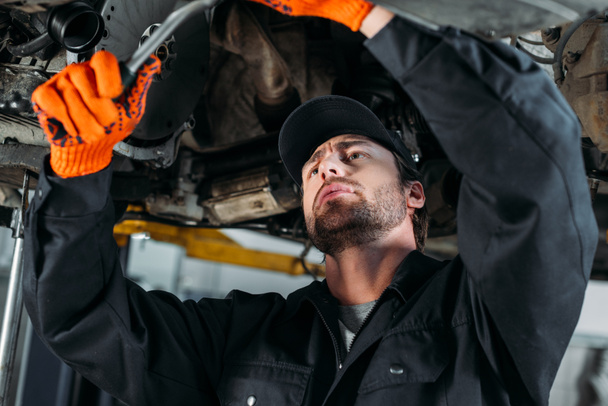 professional workman repairing a car in mechanic shop - Zdjęcie, obraz