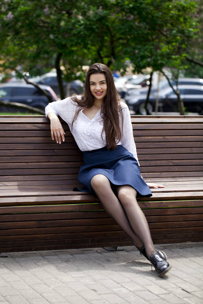 Genç, güzel esmer kadın yaz parkında bankta oturuyor. - Fotoğraf, Görsel