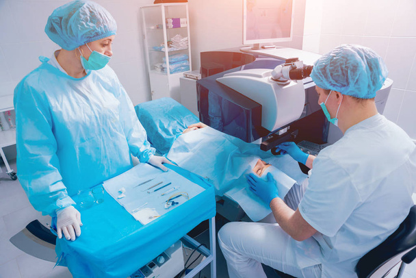 patient and team of surgeons in operating room during ophthalmic surgery - Foto, Imagen