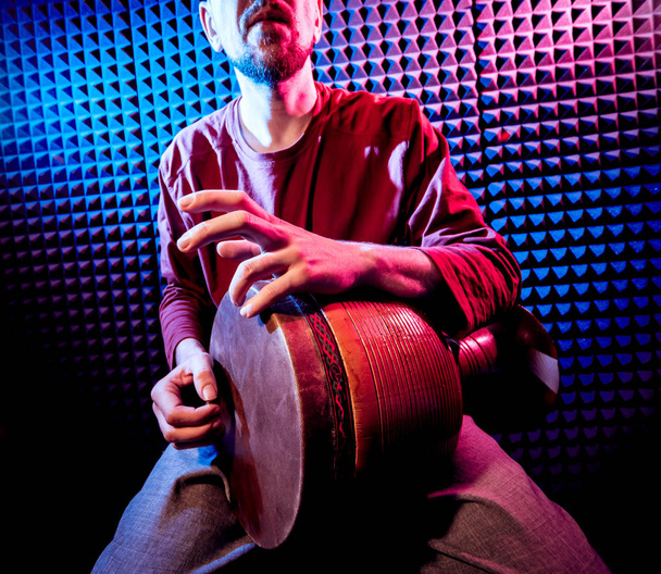 Young man playing on djembe in sound recording studio. African drums - Foto, imagen